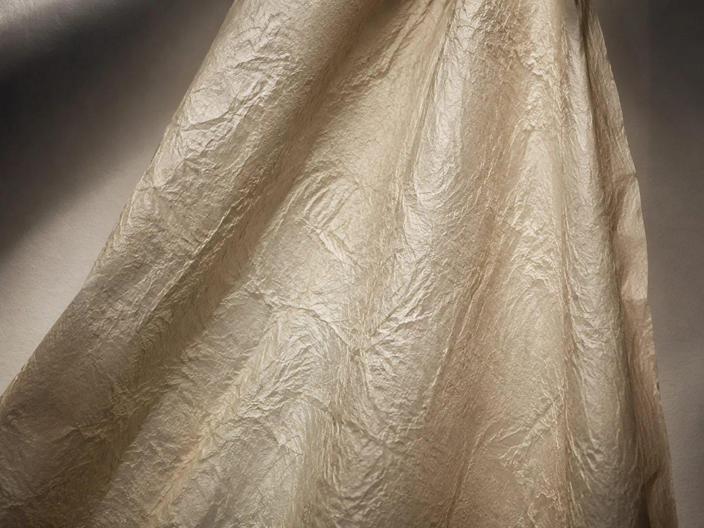 Papier texturé froissé drapé sous une lumière dramatique révélant les plis